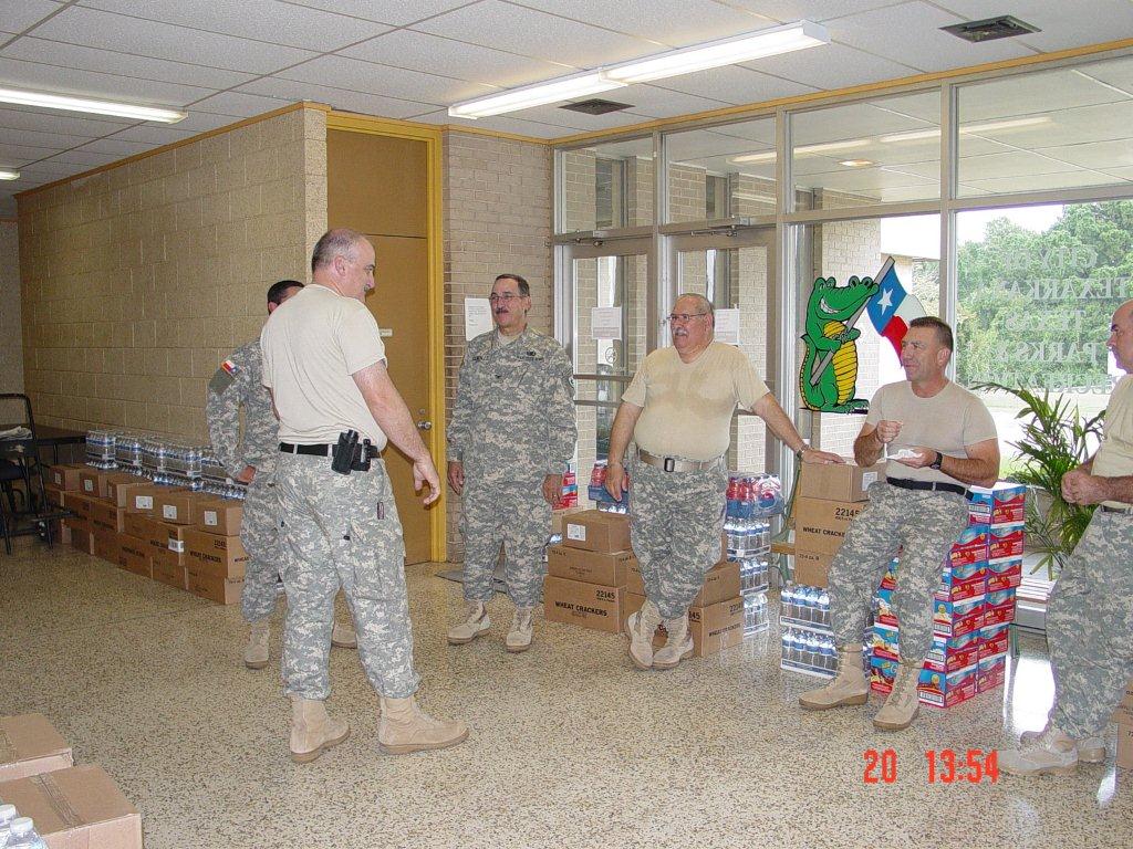 Military personnel standing near supplies in the shelter.